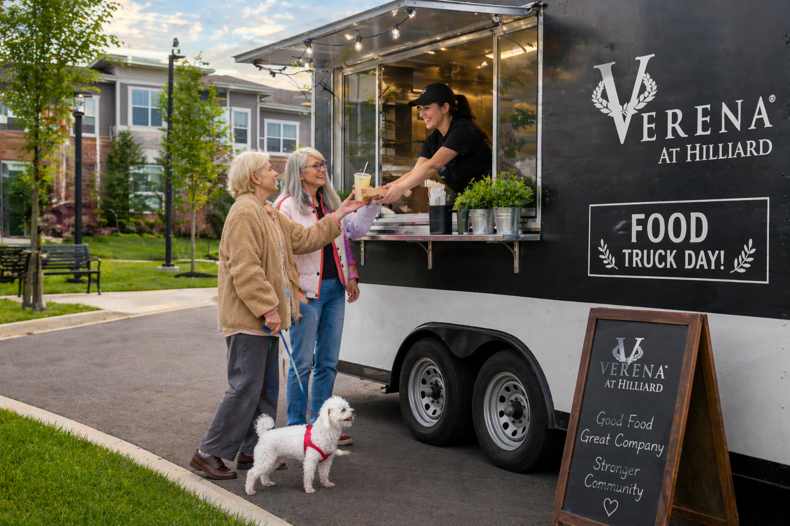 Two older women, one with a small white dog, receive food from a smiling worker at the black Verena at Hilliard food truck on Food Truck Day. A chalkboard sign in front reads, Good Food, Great Company, Stronger Community.