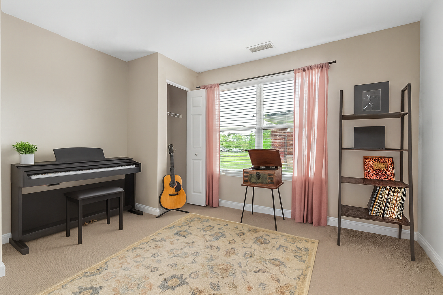 A bright music room in our two-bedroom residences features a digital piano, guitar, and open shelves holding records and art; a record player sits by a window with pink curtains, letting in natural light—giving you more space to live your way.